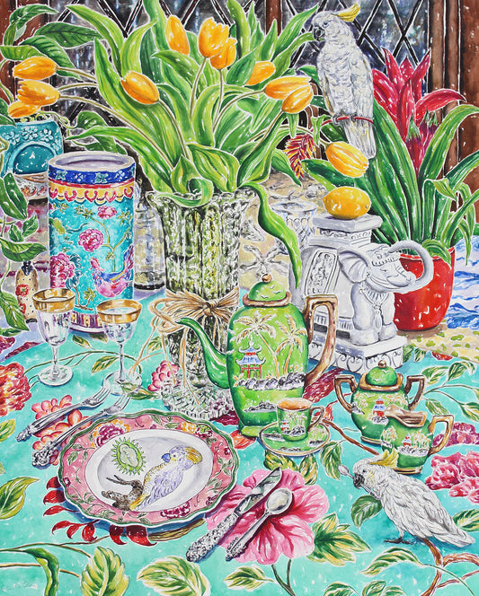 A colorful giclee print of a watercolor painting of two cockatoos in an eclectic table setting with a vase of yellow tulips and a lemon on an elephant sculpture.  Wall decor for art collectors.